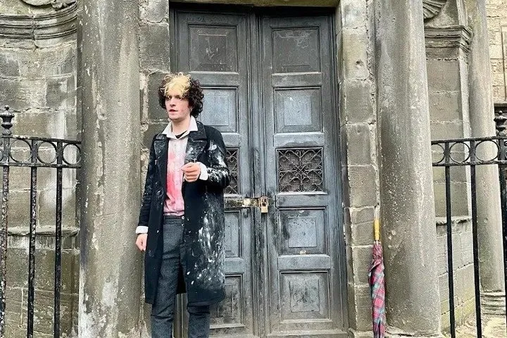 Costumed guide leading families on an afternoon Edinburgh ghost tour through an Old Town close, Scotland