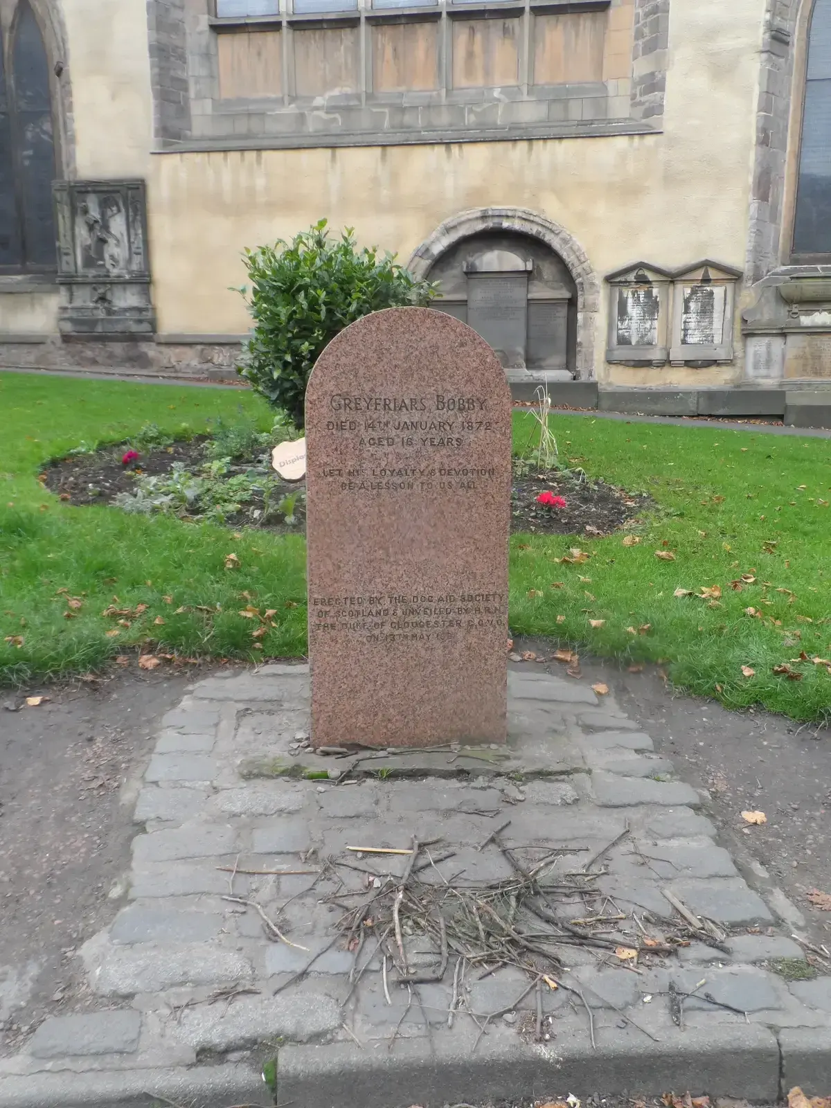 The granite headstone of Greyfriars Bobby at the entrance to Greyfriars Kirkyard, Edinburgh ghost tours, Edinburgh, Scotland